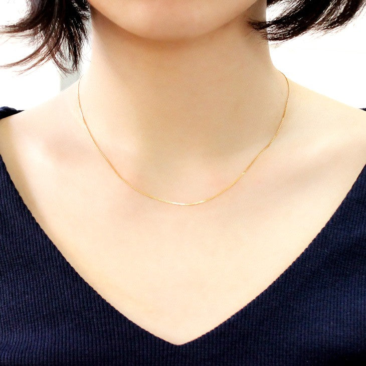 喜平チェーン K18 18金 ゴール 2面ダイヤカット ネックレス チェーン 0.85mm 40cmを着用している女性
